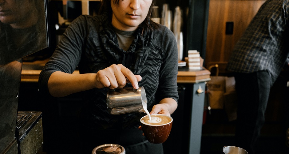Barista pours milk to create latte art